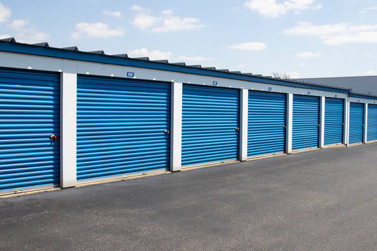 Blue roll-up doors on a row of drive-up storage units